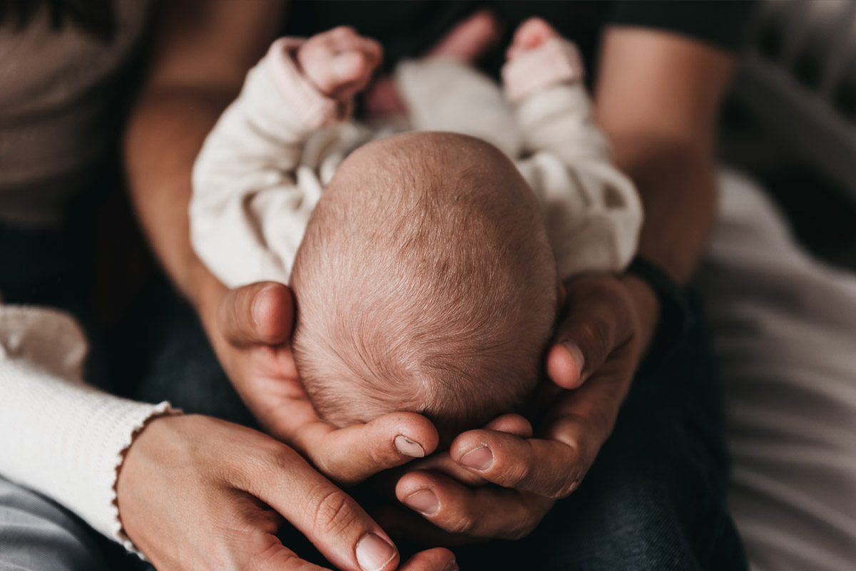 Ouders houden het hoofdje van hun pasgeboren baby in hun handen