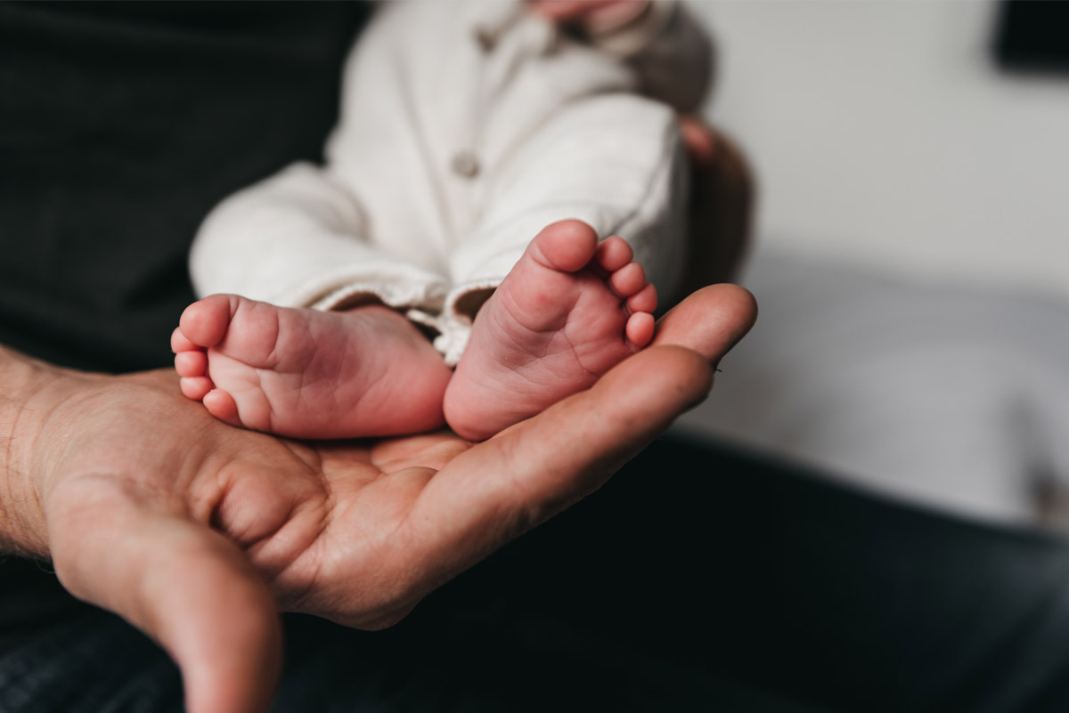 Babyvoetjes rusten in de hand van een ouder