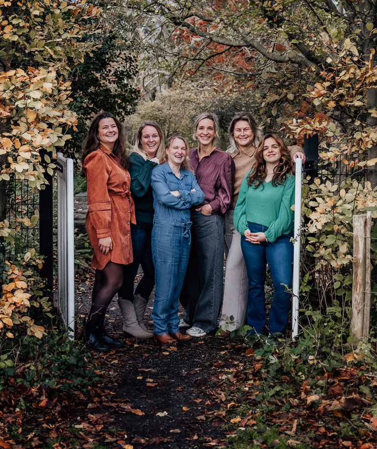 Het team van Luna Verloskundigen bij een tuinhek in de herfst